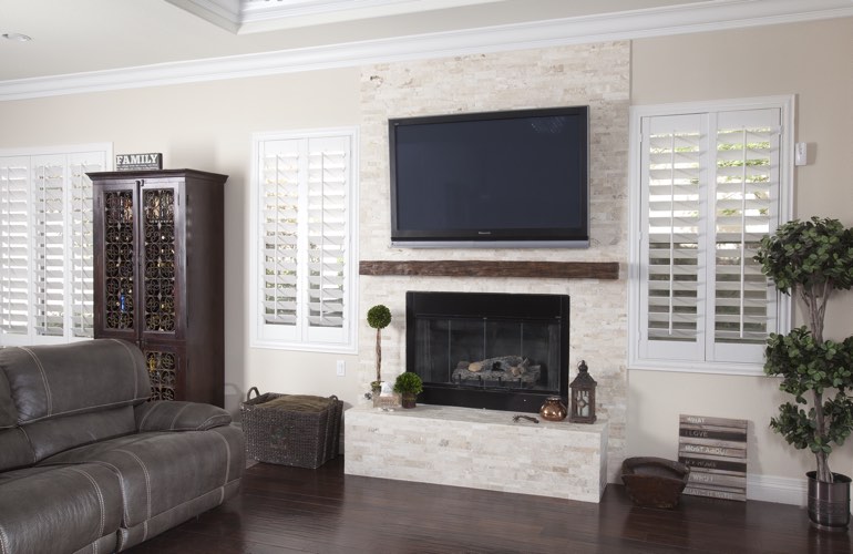 White plantation shutters in a Destin living room with dark hardwood floors.